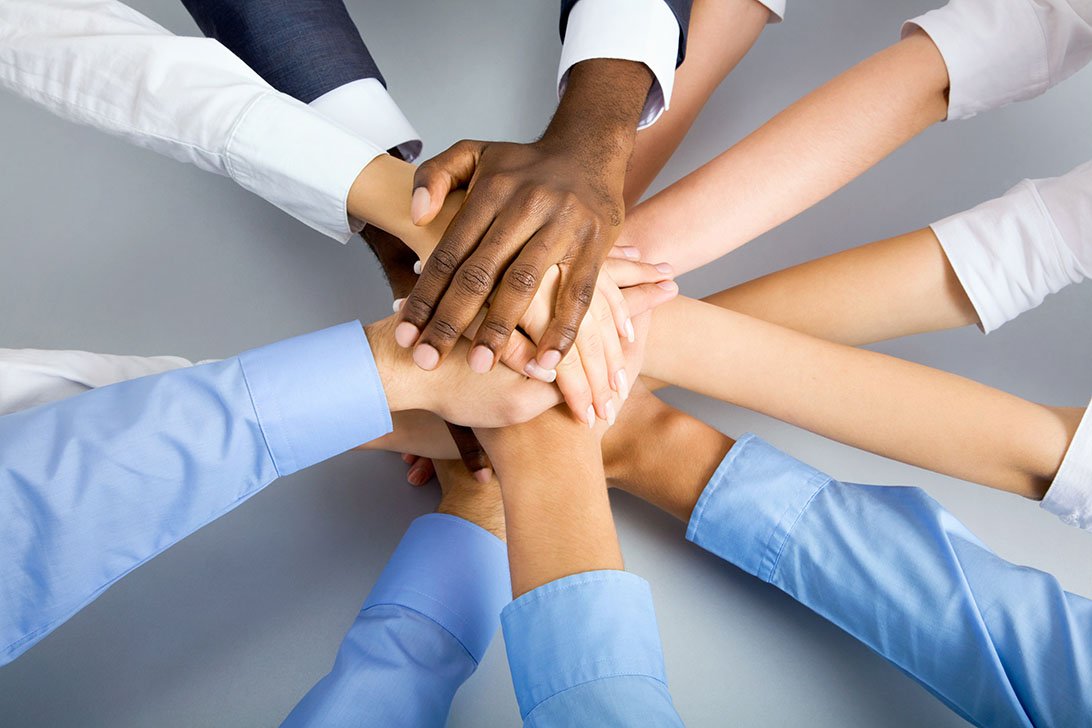 A team of professionals stacking hands together — PRAXA Marketing teamwork